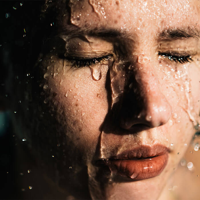 A close-up image portrays a woman doing shower and water gently cascading over her face