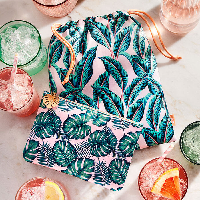 August 2022 IPSY Glam Bag and Glam Bag Plus bags together with glasses of green and pink drinks on marble table top