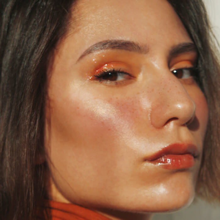 Close-up of a beautiful woman rocking a peach monochromatic makeup look