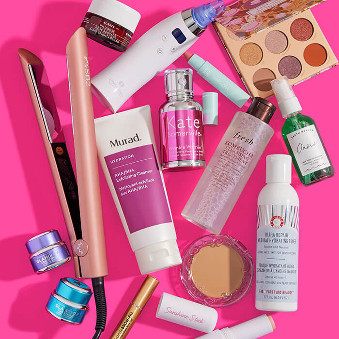 Beauty, makeup, skincare, and hair care products and tools from various brands scattered on hot pink background
