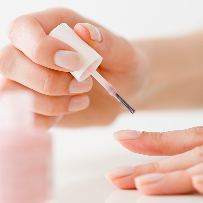 A photo of hands applying a nail polish on a white background