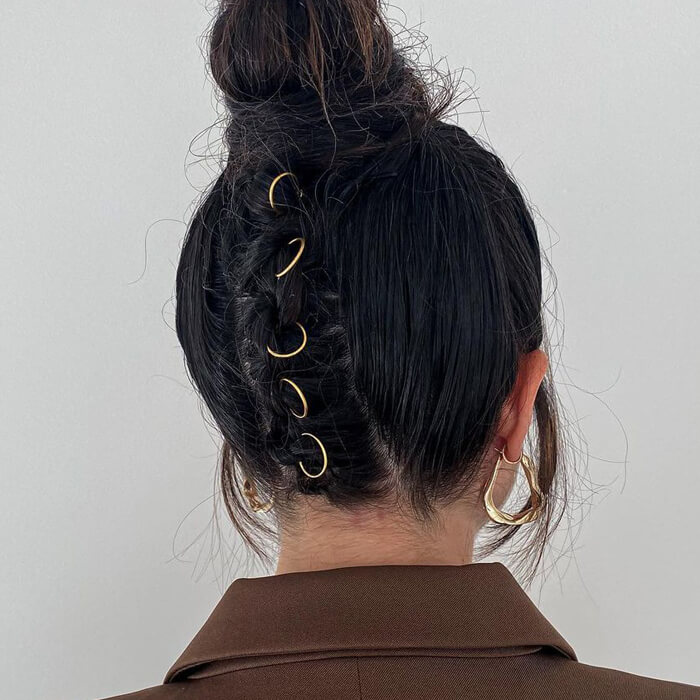 Back view of a woman's messy top bun hairstyle with hair rings