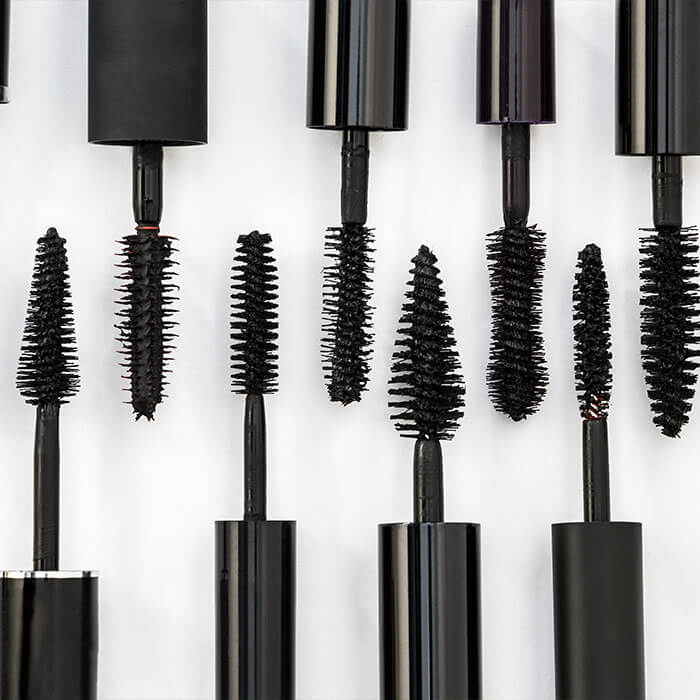 A picture featuring a row of several black mascara brushes against a white backdrop