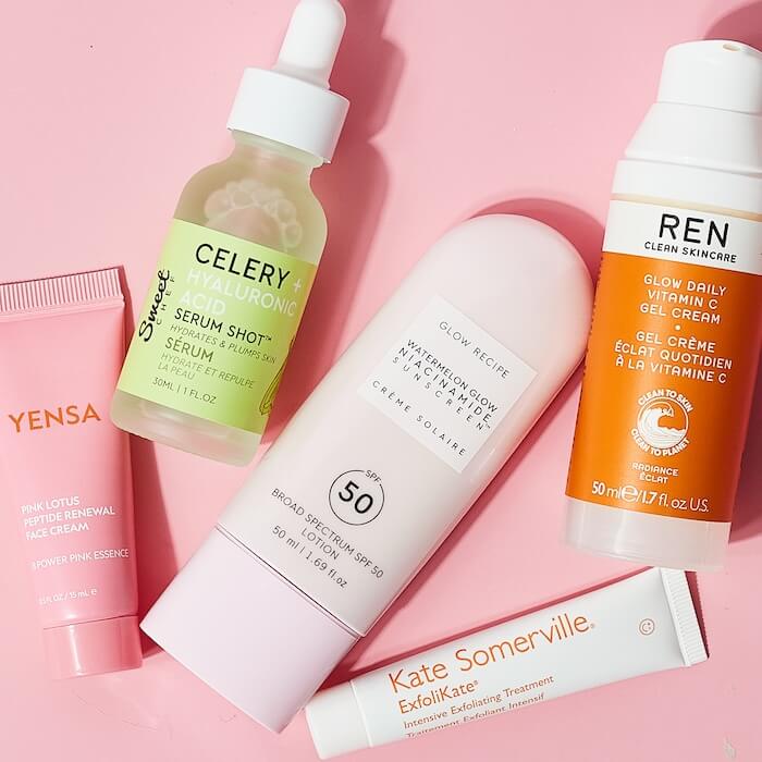 Product group of skincare from various brands on a pink background.