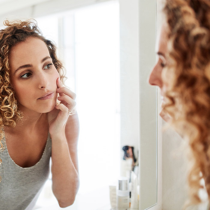 Image of a woman checking her face in the mirror