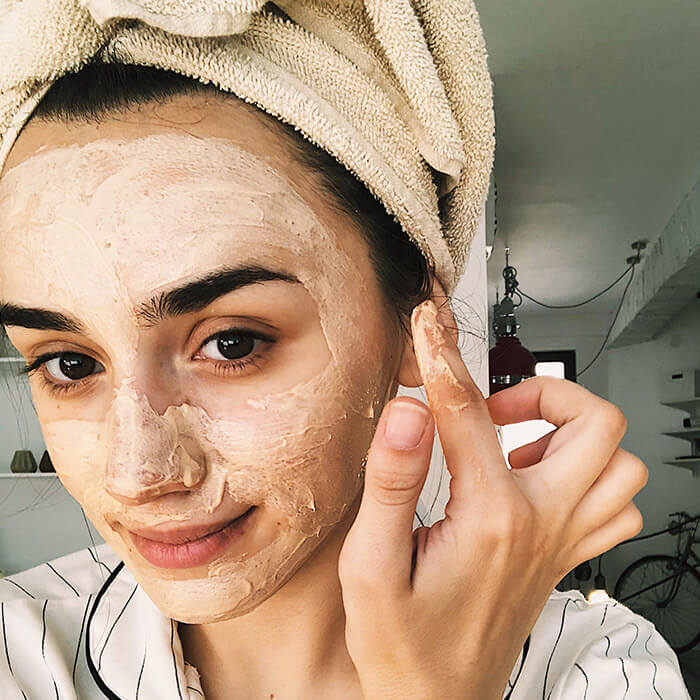 A photo of a woman applying a DIY face mask on her face