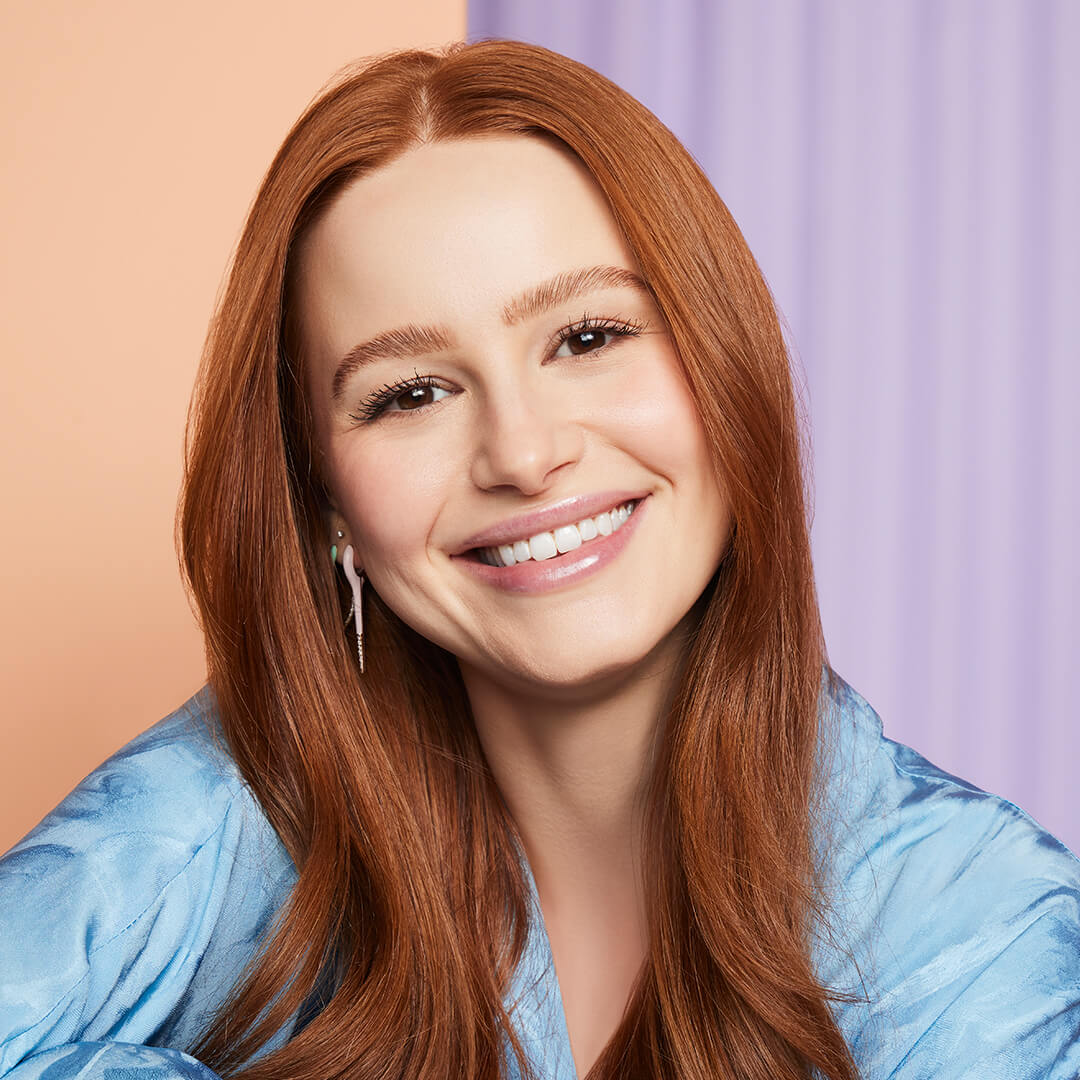 Close-up of a smiling Madelaine Petsch in a satin blue blouse