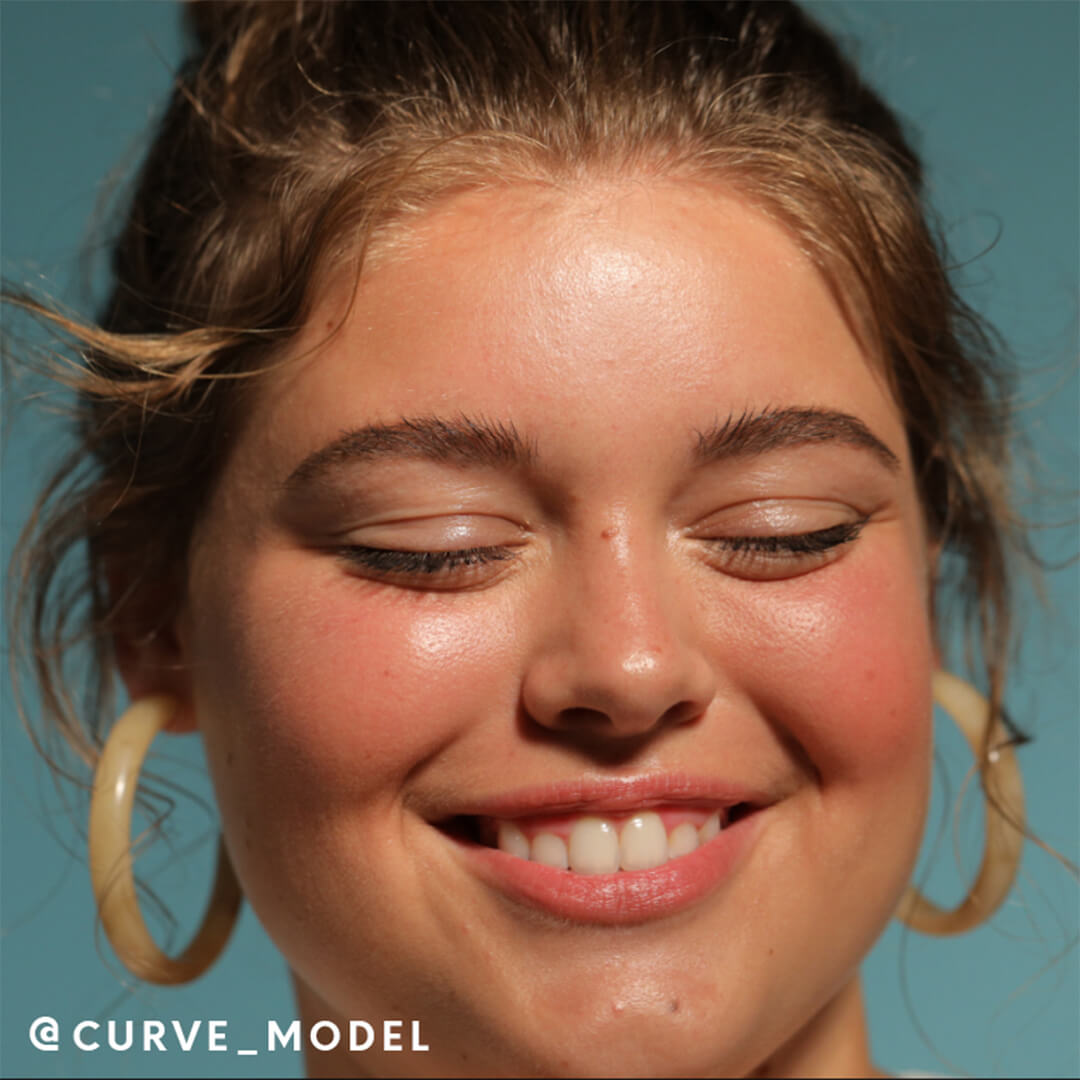 Model with a natural makeup look smiling while eyes closed