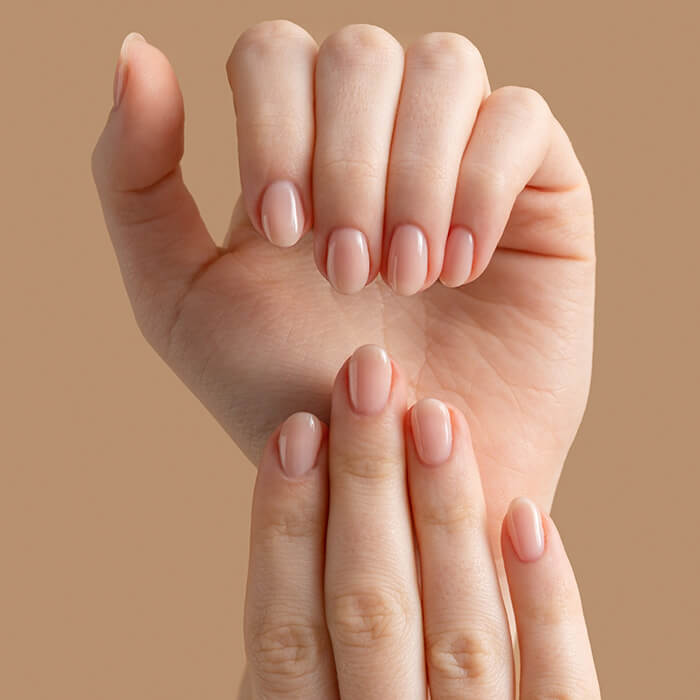 Hands of a beautiful well-groomed woman with feminine nails on a beige background.