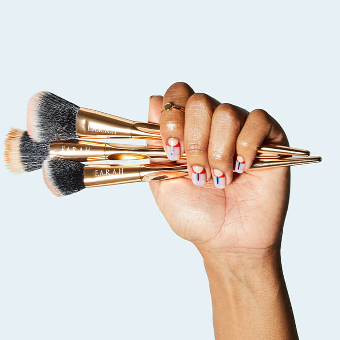 A close-up image displays a hand holding multiple F.A.R.A.H brushes, featuring colorful printed nails