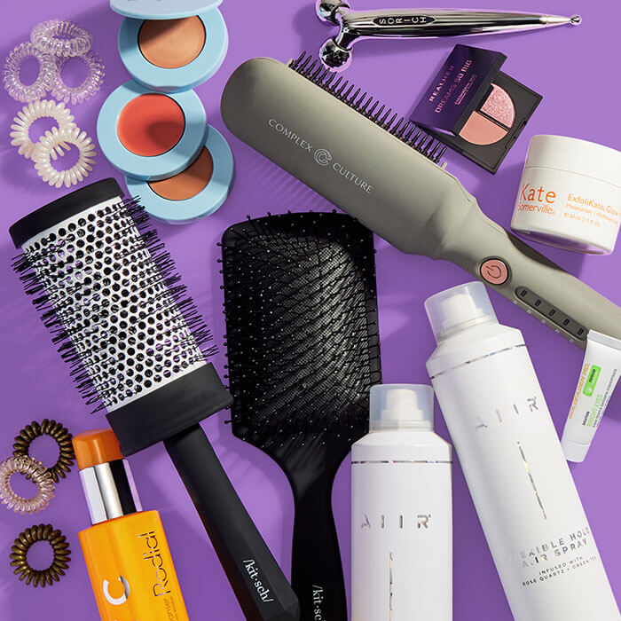 Beauty and makeup products from various brands scattered on dark purple background