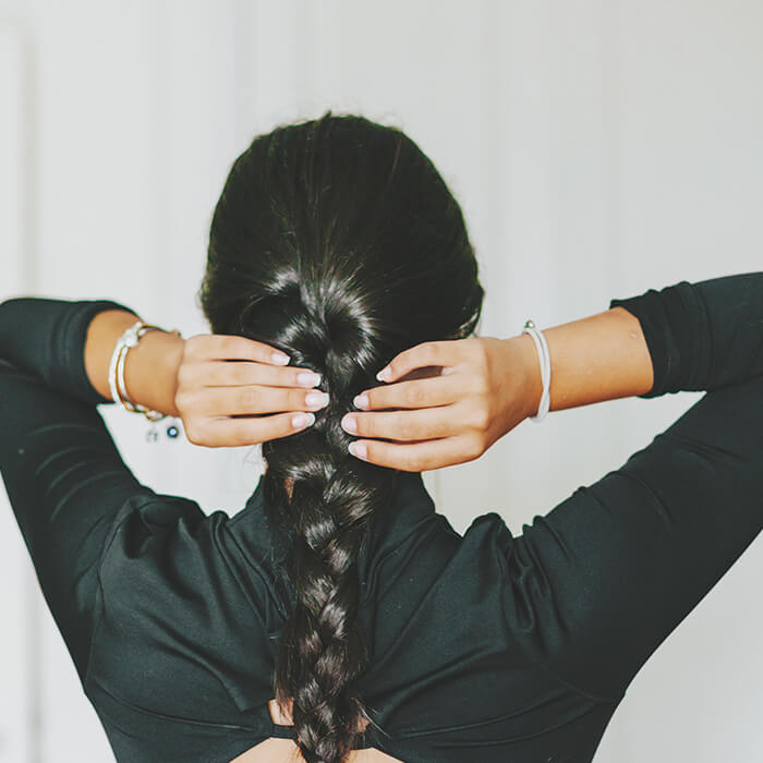 A photo of a model's back braiding her own hair