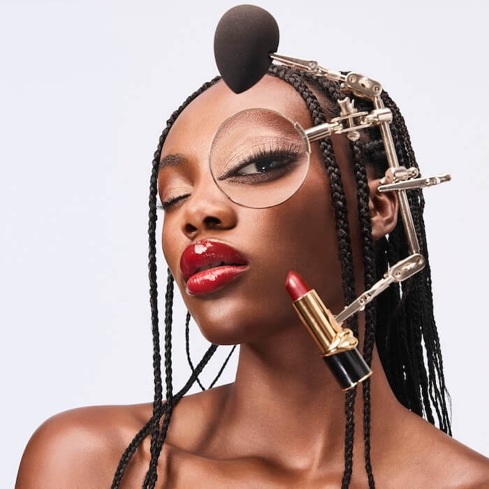 Model wearing a contraption over her head covered in beauty products and tools.