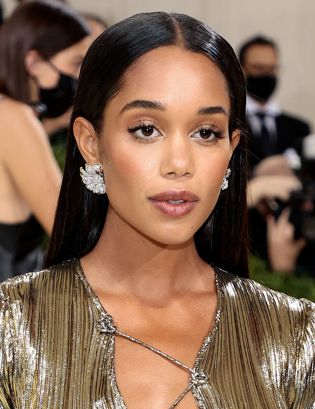 Laura Harrier looking elegant in a long and sleek hairstyle and textured gold dress