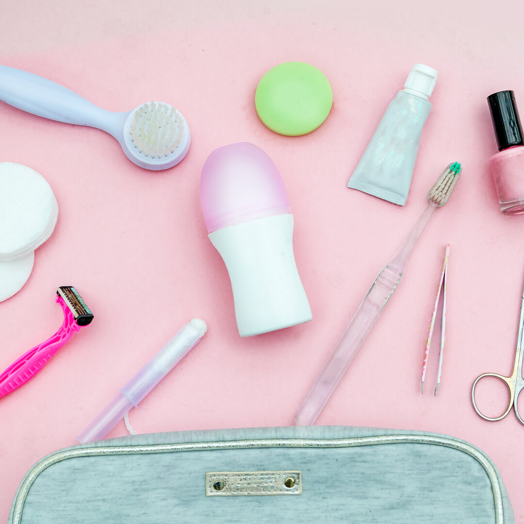 Top view of small teal pouch with hygiene products against pink background