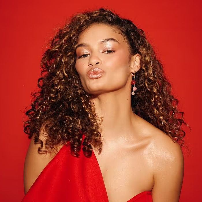 Close-up image of a model posing fiercely wearing light blue eye contacts and bold red lipstick