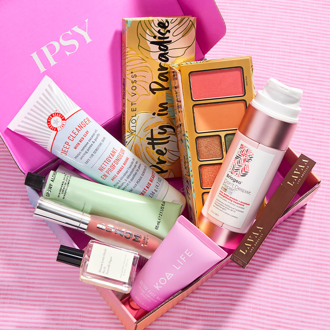 Skincare, makeup, and hair care products and tools from various brands scattered on pink background