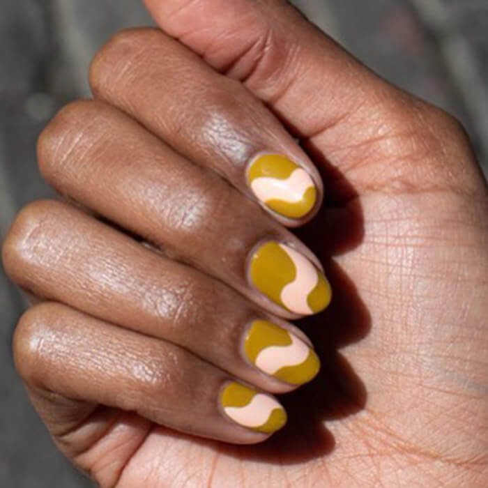 Close-up of a woman's closed fist showing her gold-toned wave nail art