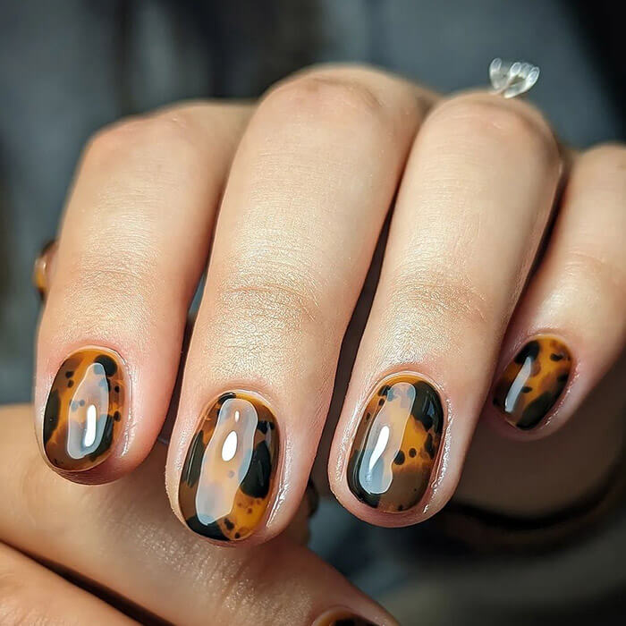 Close-up of a woman's hand with glossy, tortoise shell design nail art